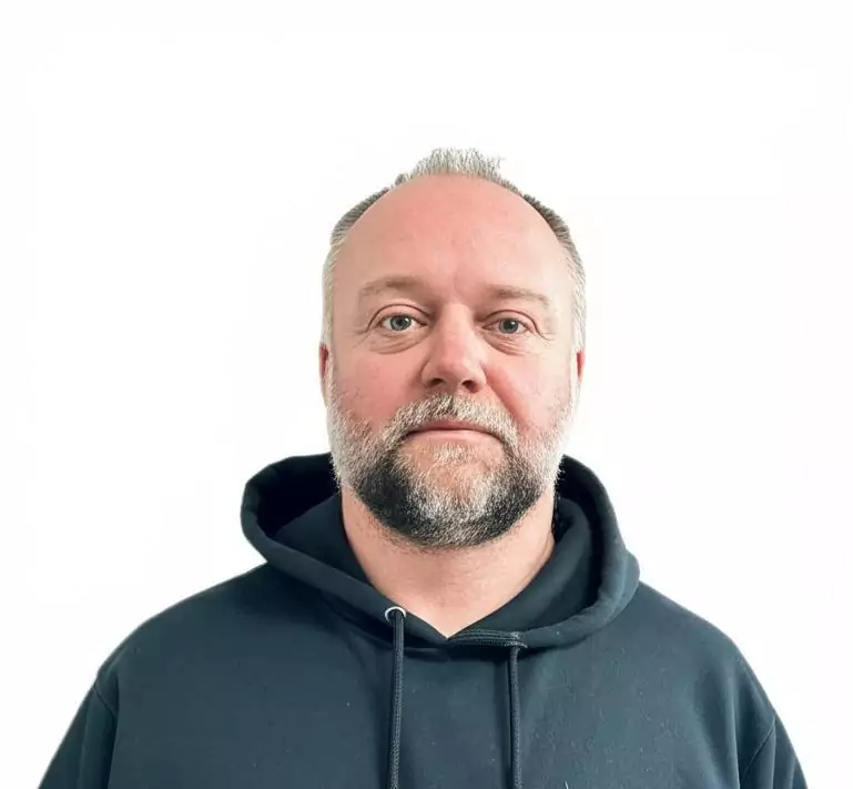 a man stands in front of a white wall