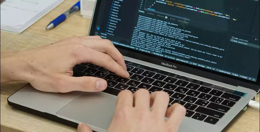 hands of a developer writing a code on a laptop