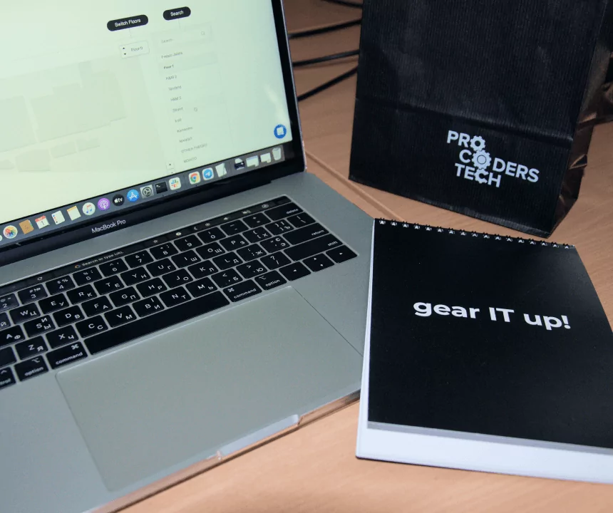 photo of a laptop and a notebook with Procoders branding on it
